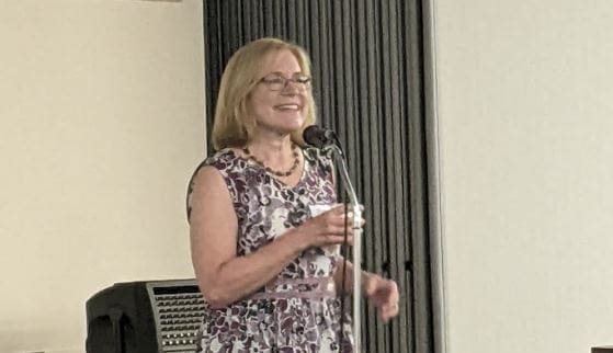 Beth Malow stands on stage, giving a presentation; volunteer spotlight; price on carbon; Tennessee