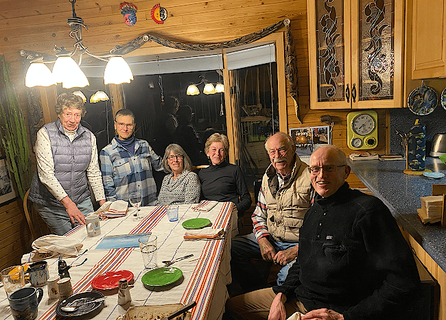 Bill Barron sits in the foreground after eating dinner with friends while on tour throughout Wyoming. A handful of older people smile at the camera from around the dinner table.