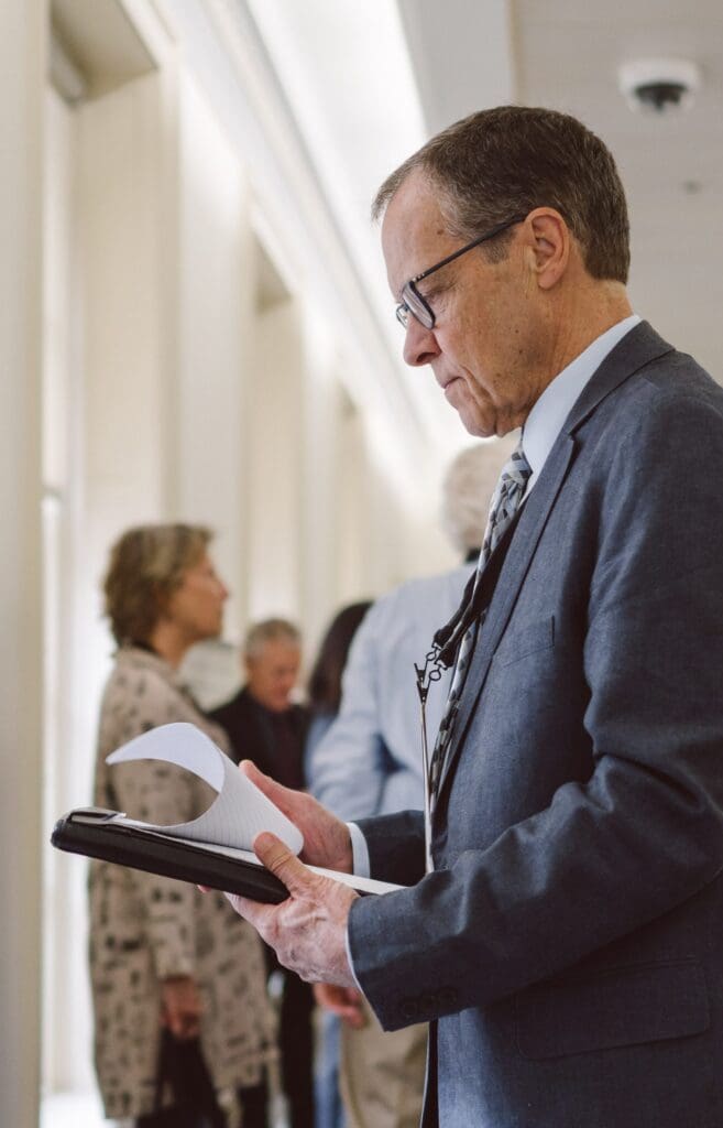A volunteer, man in a suit, reading his policy notes in the hallway of congress.